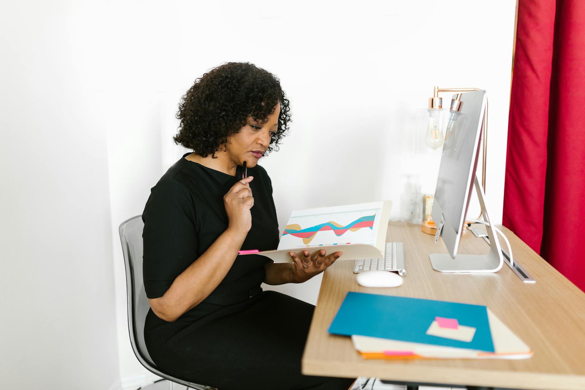 woman in black dress reading and holding a folder
